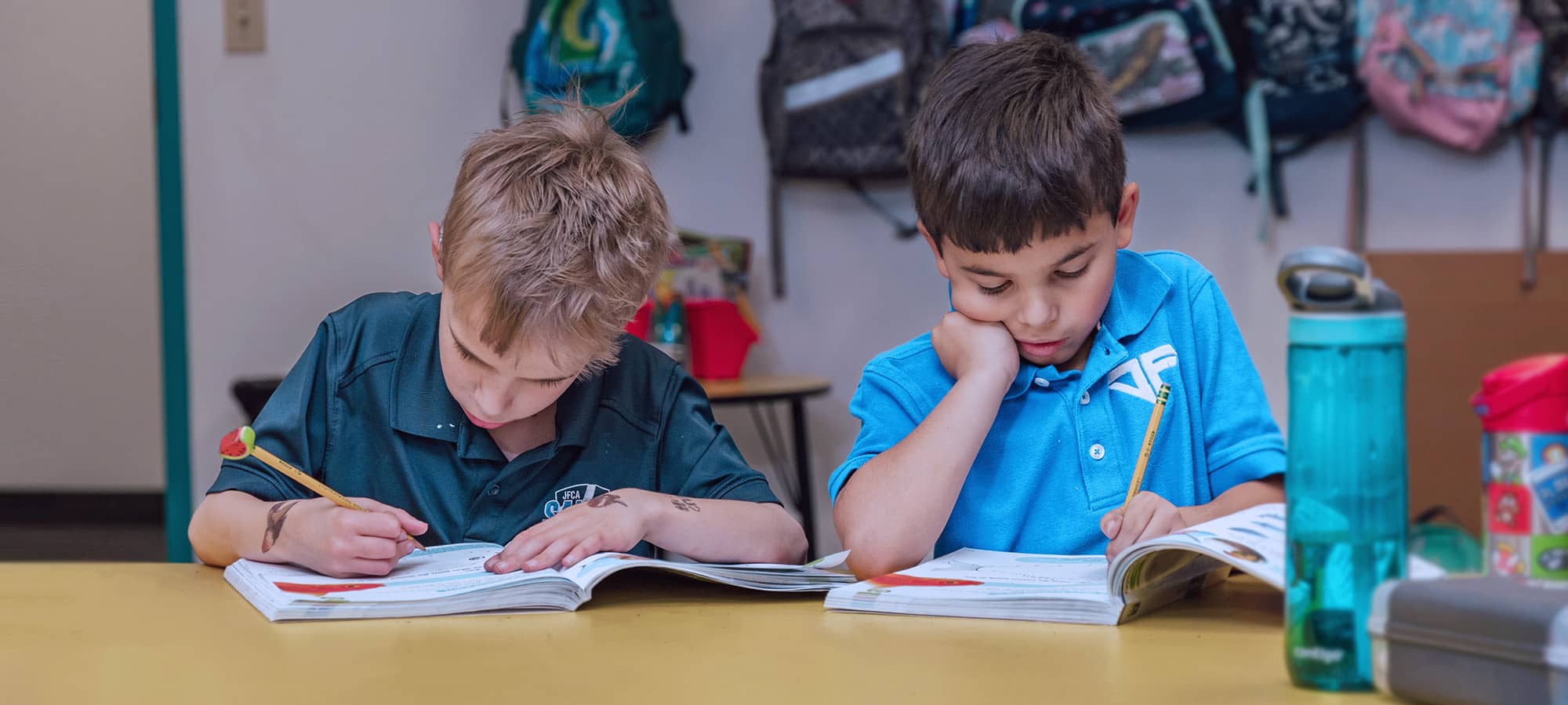 Two boys working in workbook at a table